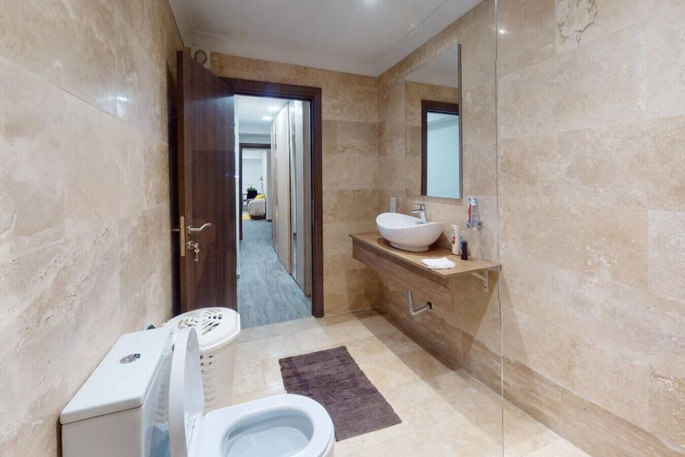 Une salle de bain comprenant des toilettes, un lavabo, un miroir et un espace douche.