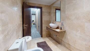 Une salle de bain comprenant des toilettes, un lavabo, un miroir et un espace douche.