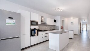 A modern kitchen with a refrigerator, oven, microwave, and a central island. - Modern 3-bedroom apartment Pieta (Tal-Pietà)