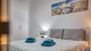 A bedroom with a bed, pillows, a lamp, and a painting on the wall. - Modern 3-bedroom apartment Pieta (Tal-Pietà)