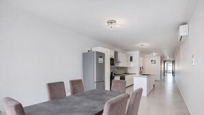 A modern kitchen with white cabinets, a grey countertop, and a dining area with a grey table and chairs. - Modern 3-bedroom apartment Pieta (Tal-Pietà)