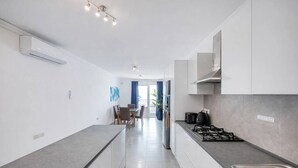 A modern kitchen with a central island, a dining area with chairs, and a view to a balcony. - Modern 3-bedroom apartment Pieta (Tal-Pietà)