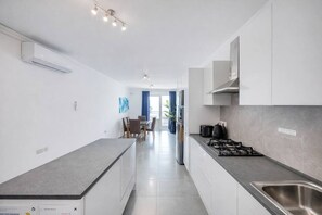 Une cuisine moderne dotée d’un îlot central, d’un coin repas avec des chaises et donnant sur un balcon.