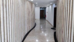Un pasillo con techo curvo, iluminación empotrada y un borde negro a lo largo del suelo.