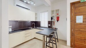 A modern kitchen with white cabinets, a black countertop, and a wooden door. - Modern 2-bedroom apartment in Gzira (Il-Gżira)
