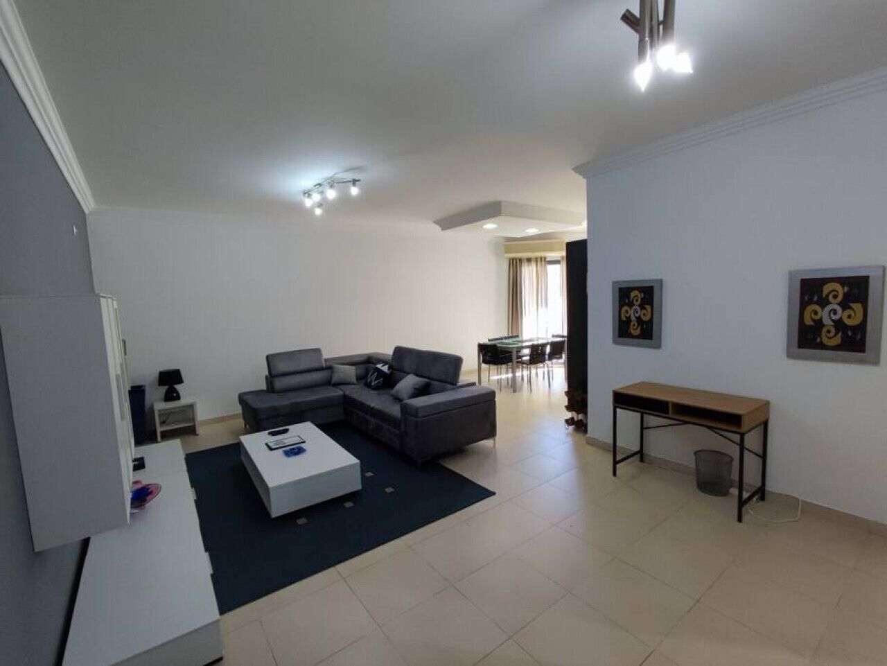A modern living room with a sectional sofa, a coffee table, and a dining area with a bench and table.
