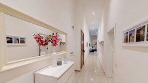 A hotel corridor with a white reception desk, a mirror, and framed pictures on the walls. - Spacious 3 bedroom maisonette (Tas-Sliema)