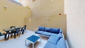 A small outdoor patio with a blue sofa, a table with chairs, and a small blue table. - Spacious 3 bedroom maisonette (Tas-Sliema)