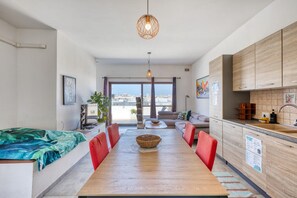 A modern apartment with a dining area, kitchen, and a balcony with a city view.