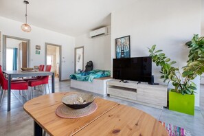 Ein modernes Wohnzimmer mit Essbereich, einem Flachbildfernseher und einer Zimmerpflanze.