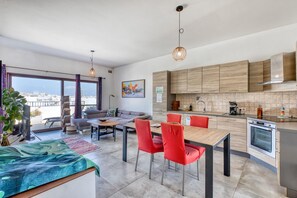 Ein modernes Apartment mit Essbereich, Küche und einem Balkon mit Blick auf die Stadt.