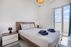 A hotel room with a bed, two bedside tables with lamps, a window with a view, and a ceiling light.