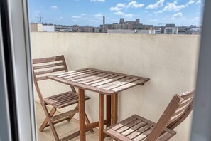 Ein Holztisch mit Stühlen auf einem Balkon mit Blick auf die Stadt.