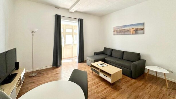 Una sala de estar moderna con sofá, mesa de centro y mueble para televisión.
