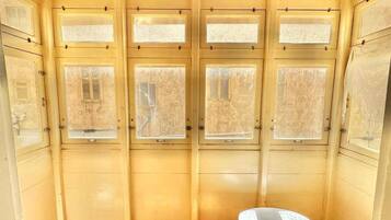 Una habitación con cuatro ventanas, una silla blanca y suelo de madera.
