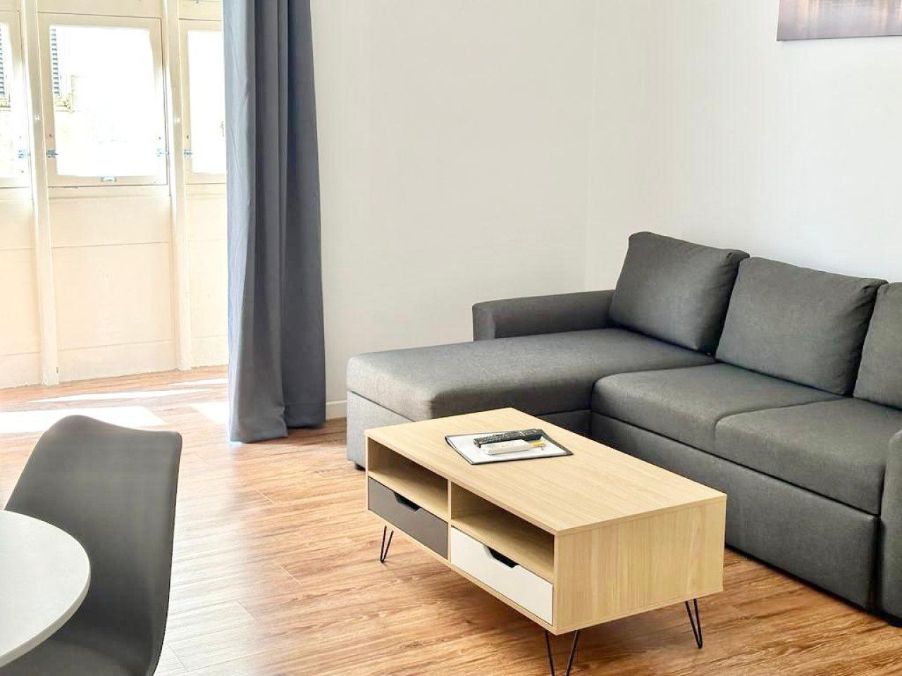 Un soggiorno moderno con un divano grigio, un tavolino in legno e una poltrona grigia.