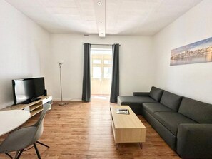 Un salon moderne avec un téléviseur à écran plat, un canapé, une table basse et un bureau.