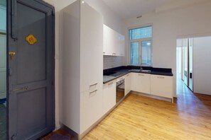 Une cuisine moderne avec des armoires blanches, un comptoir noir et une fenêtre.