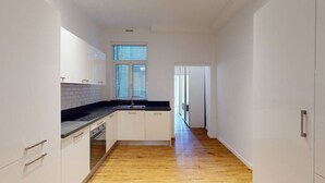 Eine schmale Küche mit weißen Schränken, einer schwarzen Arbeitsplatte und Holzboden.