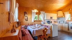 A cozy cabin interior with a dining area, wooden walls, and a kitchen. - Chalet Panoramique Avec Sauna Avec vue sur le LAC Leman et Montagnes (Évian-les-Bains)