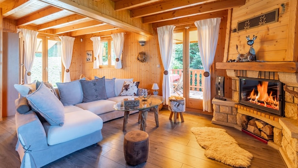 A cozy cabin interior with a wooden ceiling, a fireplace, a sofa, and a glass coffee table. - Chalet Panoramique Avec Sauna Avec vue sur le LAC Leman et Montagnes (Évian-les-Bains)