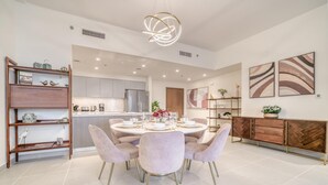 Une cuisine moderne dotée d’un îlot central, un coin repas avec une table ronde et des chaises, et un espace salon avec un canapé et une table basse.