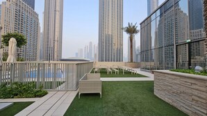 Un jardin sur le toit, doté d’une pelouse artificielle, d’espaces aménagés pour s’asseoir et offrant une vue sur les immeubles environnants.