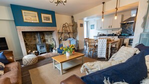 A cozy living room with a fireplace, a dining area, and a kitchen.