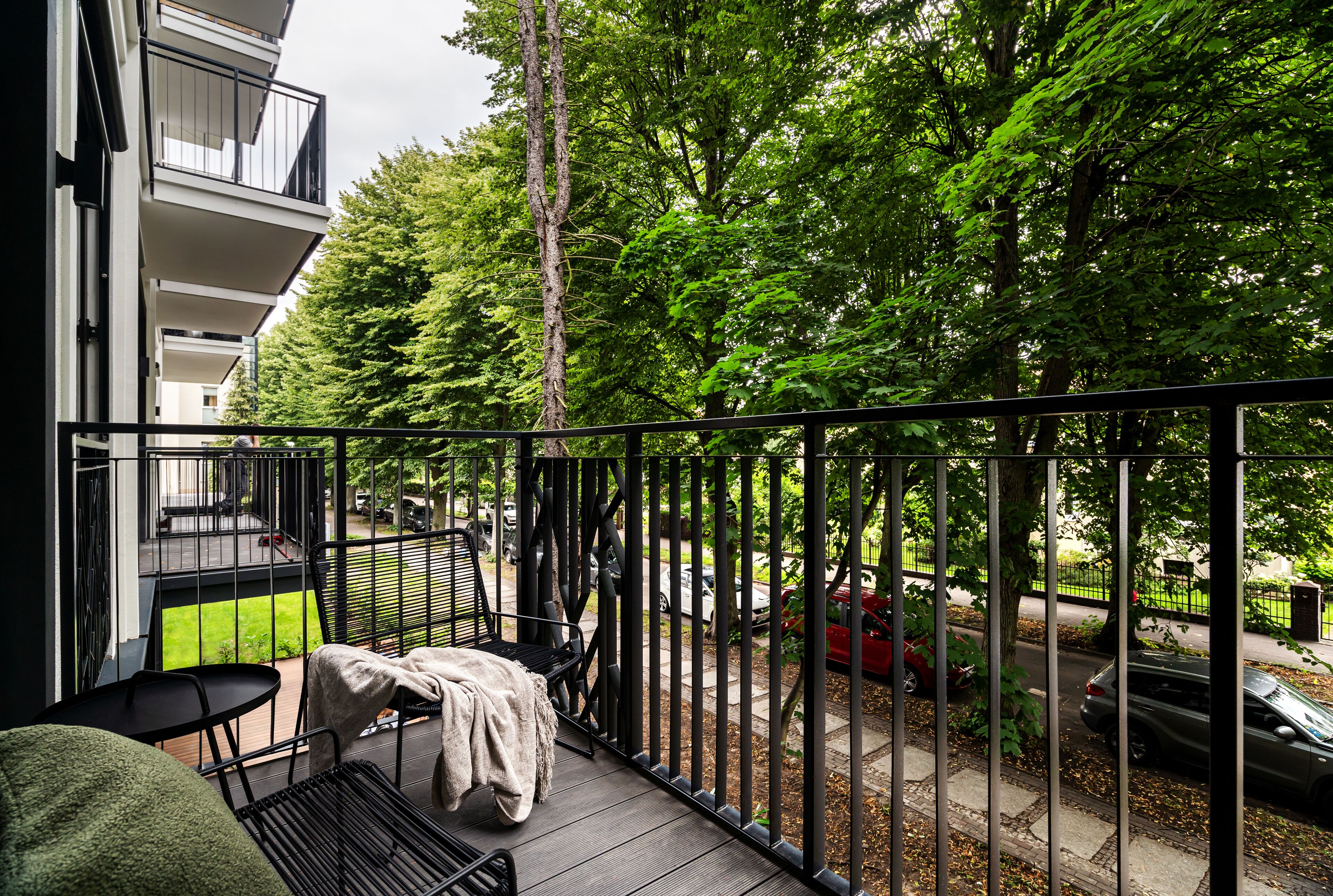 Een balkon met uitzicht op een straat, een stoel en een tafel.