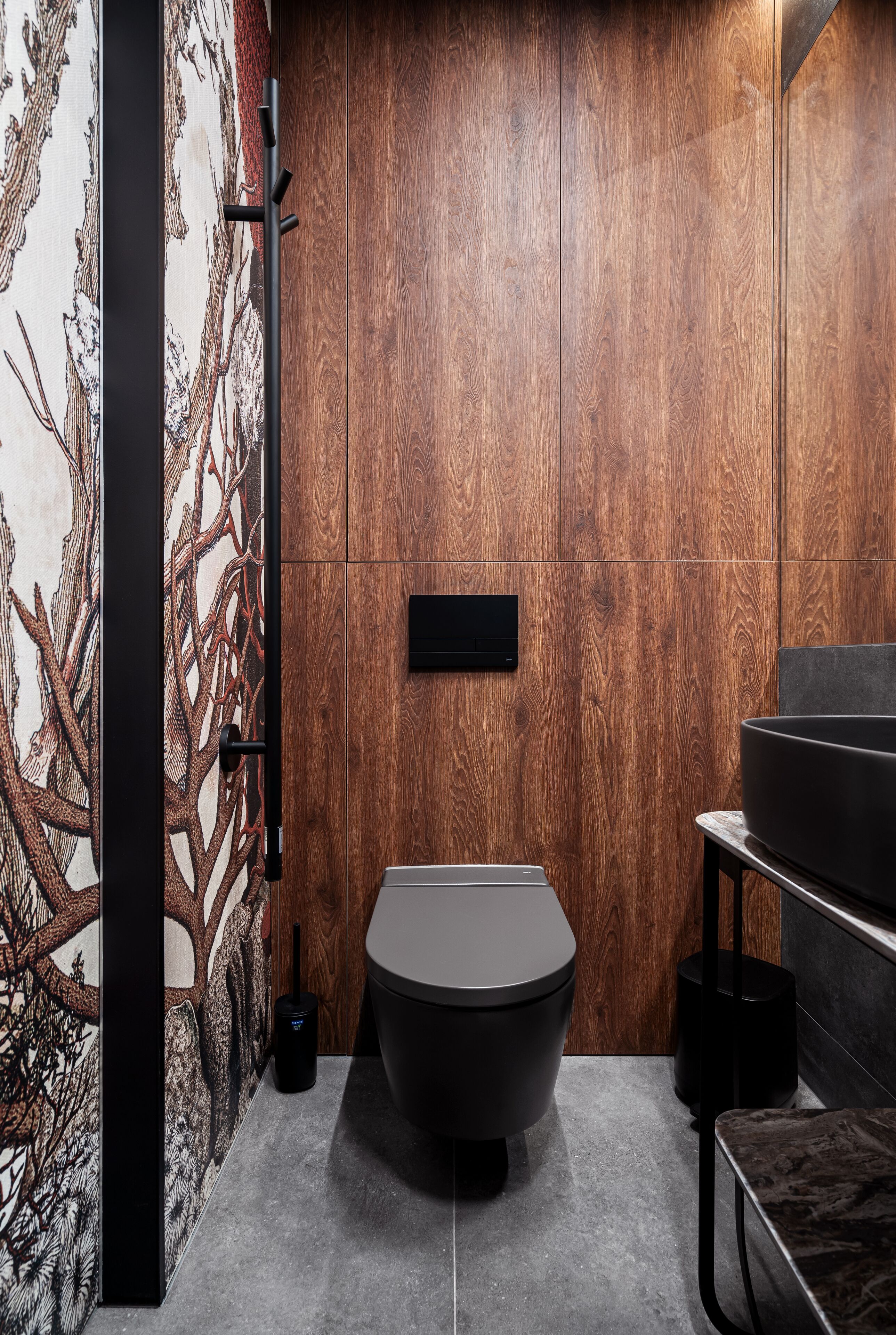 A modern bathroom with a wooden wall, a black toilet, and a black sink.