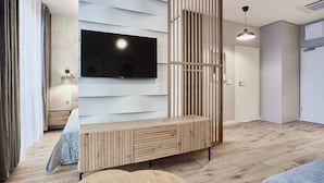 A modern living room with a wooden entertainment unit, a flat-screen TV, and a pendant light. - Apartamenty Świnoujście - Seaside Garden (Swinoujscie)