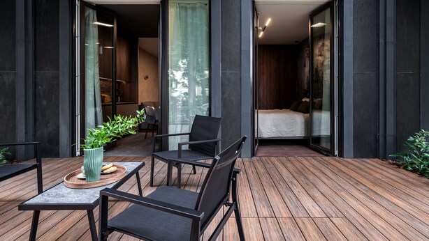 A modern outdoor seating area with a wooden deck, a table with chairs, and a potted plant. - Apartamenty Świnoujście - Seaside Garden (Swinoujscie)