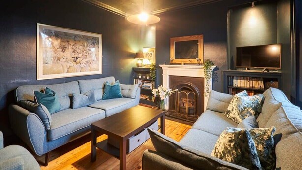 Una sala de estar con chimenea, televisor y una obra de arte grande enmarcada en la pared.