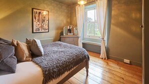 Un dormitorio con cama, cómoda, espejo y ventana con cortinas.