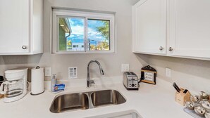 A modern kitchen with a stainless steel sink, a coffee maker, a toaster, and a window with a view of the outside. - Mountain view | Games, Patio and BBQ in CO Springs (Colorado Springs)