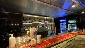 A bar area with shelves of liquor bottles, a Pepsi refrigerator, and a Carlsberg fridge. - The Boat - Hostel&Chill (Kraków)