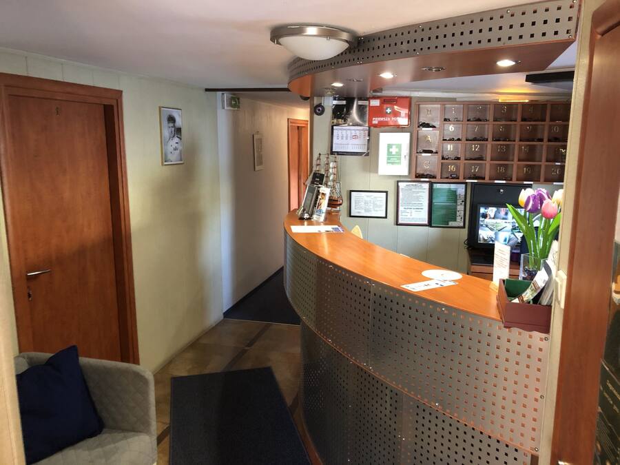 A reception area with a wooden reception desk, a coat rack, a television, and a wall-mounted shoe rack.