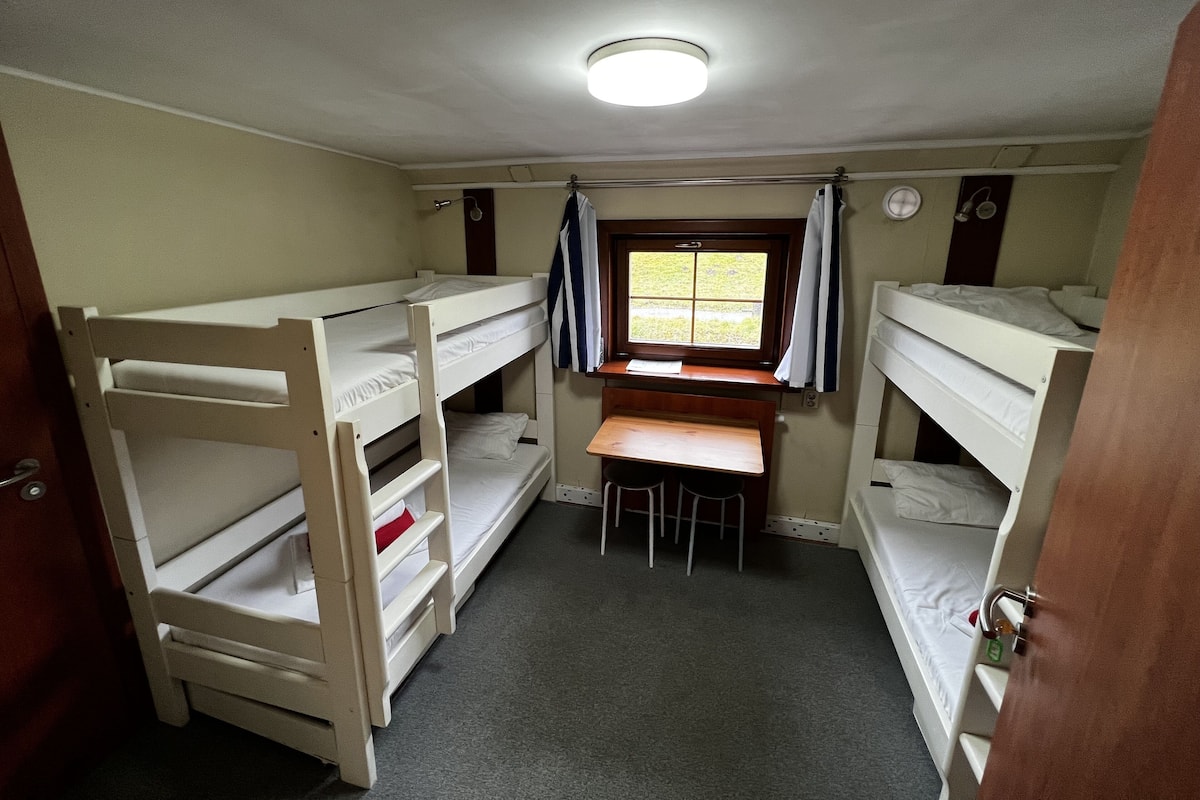 A compact room with bunk beds, a desk, and a window.