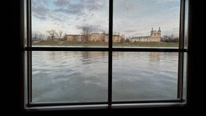 A window with a view of a building across a body of water. - The Boat - Hostel&Chill (Kraków)