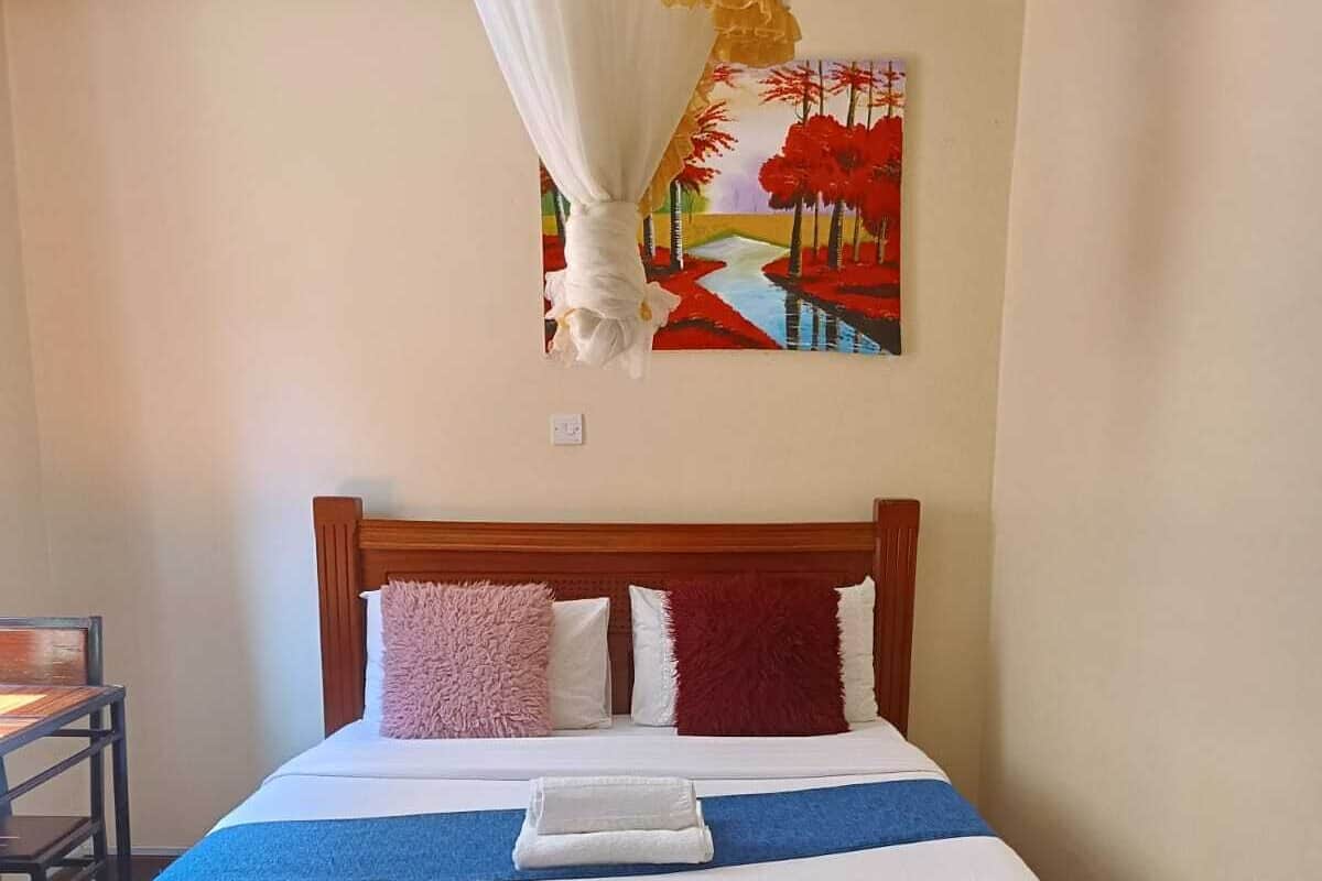 A neatly made bed with a wooden headboard, a blue and white bedspread, and two pillows. A white canopy is draped over the bed.