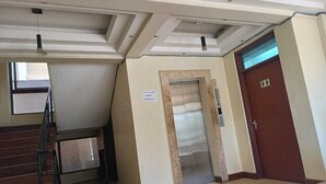 A hotel lobby with a staircase, an elevator, and a door marked with an accessibility symbol. - Lux Suites kipande Road Studio Apartment (Nairobi)