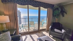 Een balkon met uitzicht op de oceaan, een bank, een stoel en een tafel met een lamp.