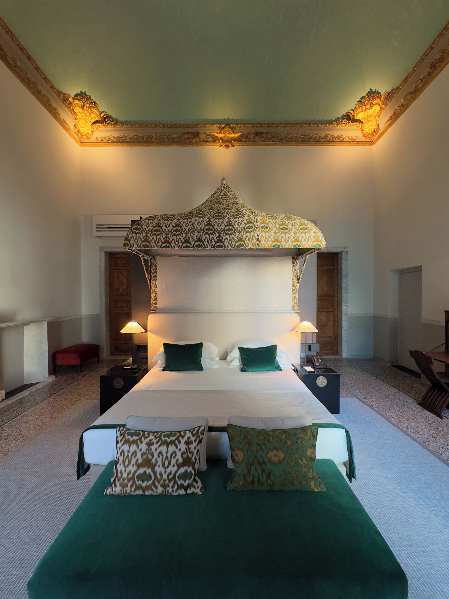 A spacious bedroom with a large bed, two bedside tables, a canopy bed, and a carpeted floor.