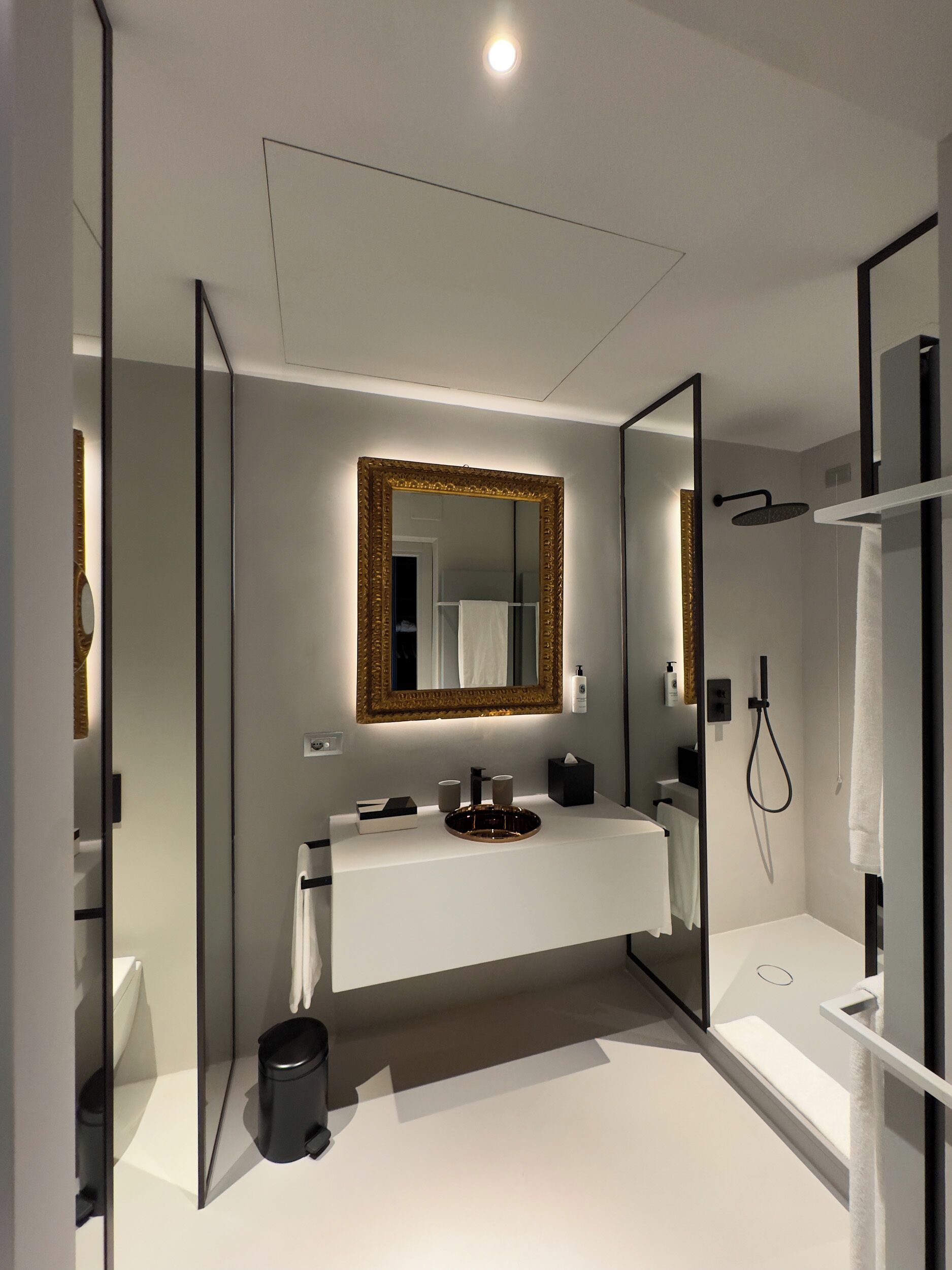 Une salle de bain moderne avec un meuble-lavabo blanc, un grand miroir et un espace douche.