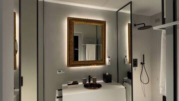 Une salle de bain moderne avec un meuble-lavabo blanc, un grand miroir et un espace douche.