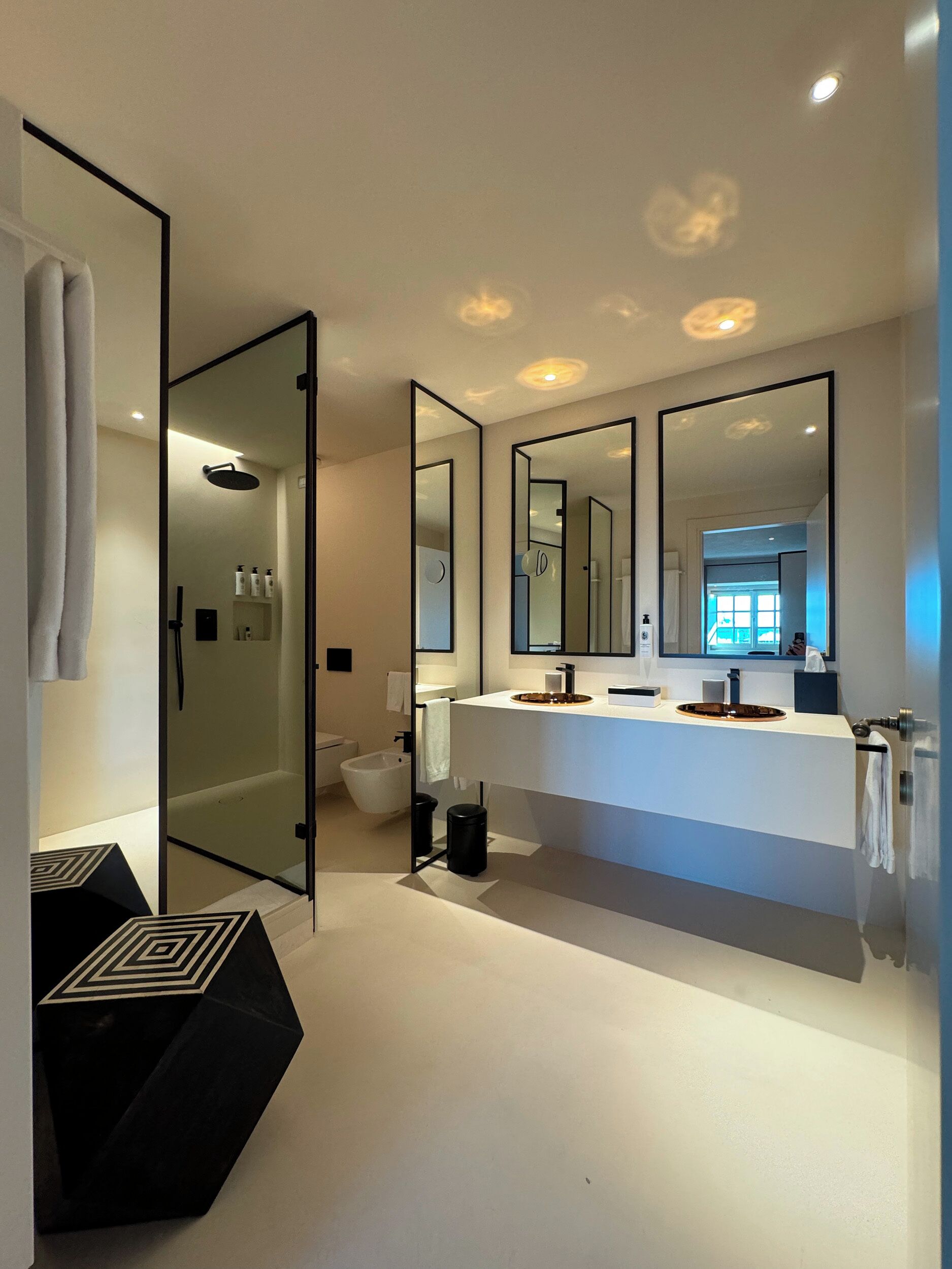 Une salle de bain moderne dotée d’un grand miroir, d’une douche à l’italienne et d’un meuble-lavabo.