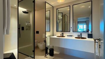 Une salle de bain moderne dotée d’un grand miroir, d’une douche à l’italienne et d’un meuble-lavabo.