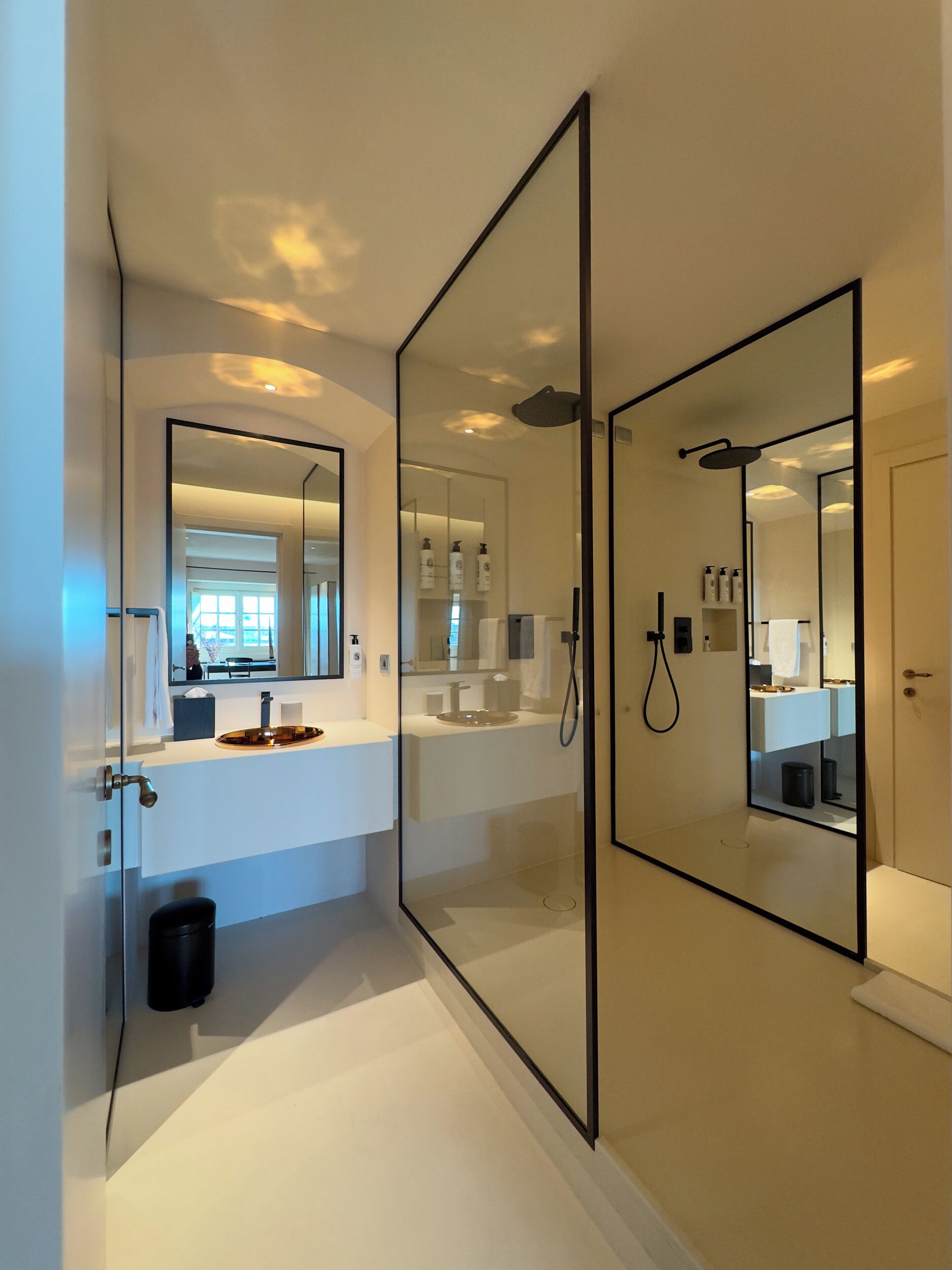 A modern bathroom with a glass-enclosed shower, a large mirror, and a white vanity.