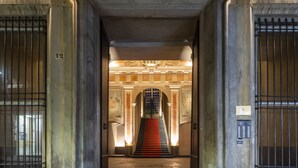 A grand entrance with a staircase leading to an upper level, flanked by ornate columns and metal gates. - Palazzo Durazzo Suites (Genoa)