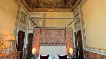 Ein luxuriöses Hotelzimmer mit Himmelbett, aufwändiger Deckenmalerei und Marmorboden.